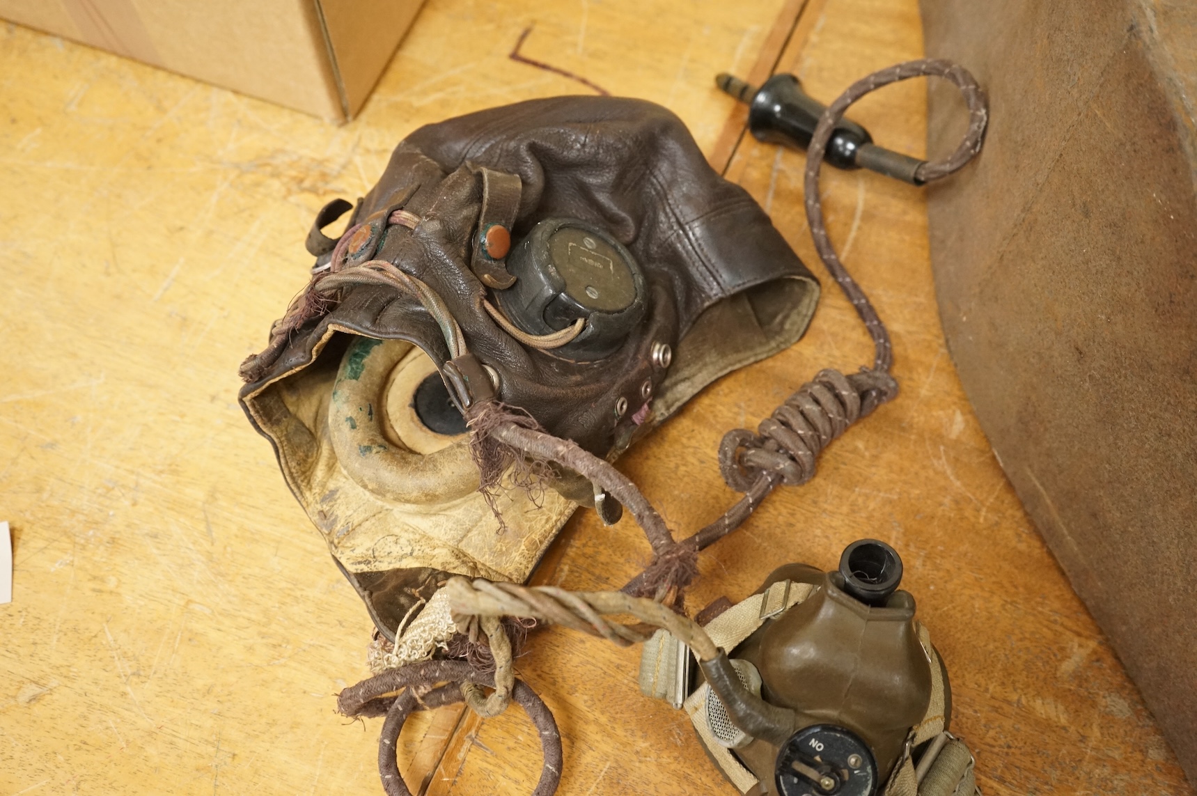 A WWII RAF Air Ministry aviator’s leather head-gear, with built-in padded headphones, oxygen mask with microphone and other electrics incorporated into it, marked with a crown and ‘AM 10A/13466’ to one earpiece, together